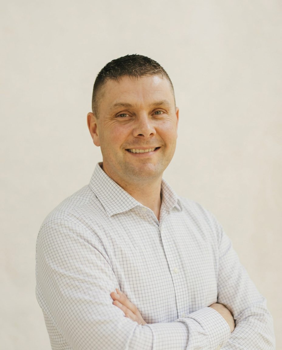 Portrait of Dave Miller, personal mental fitness trainer and founder of White Rock Mental Fitness, smiling with arms folded in a light checked shirt